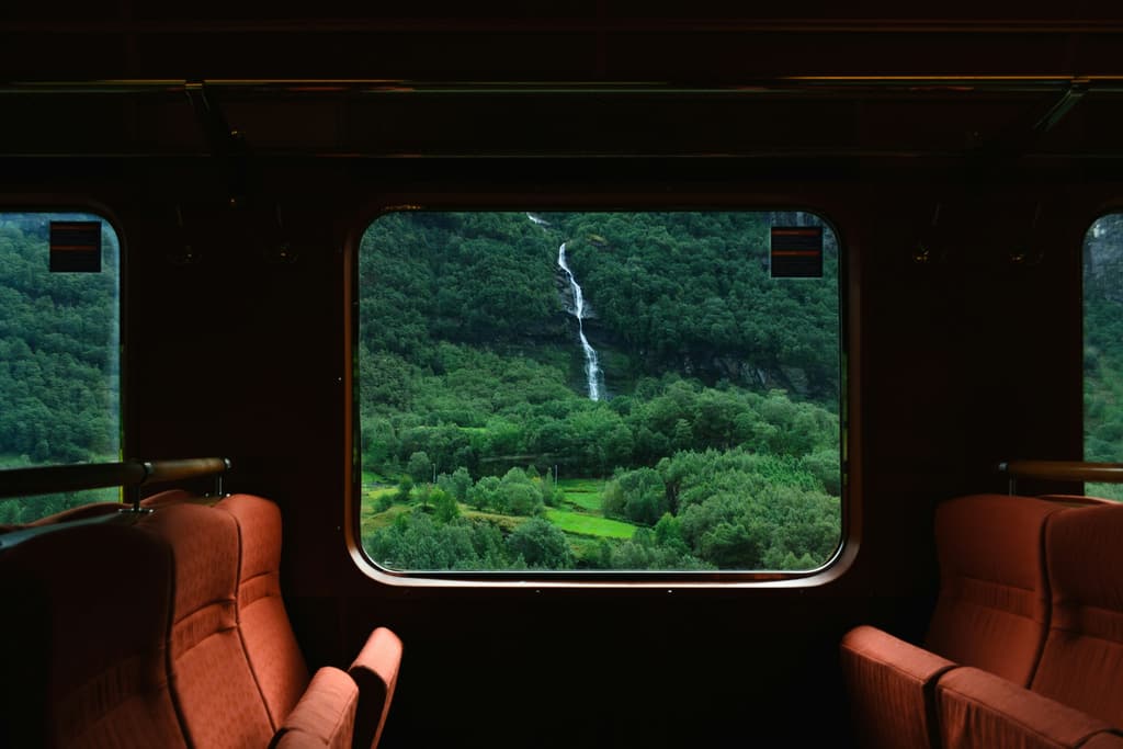 A green valley and a waterfall seen through a train window